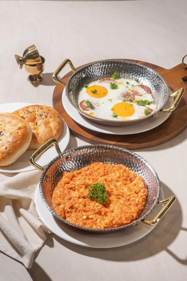Menemen scrambled eggs and pan-fried sucuk with eggs in copper pans